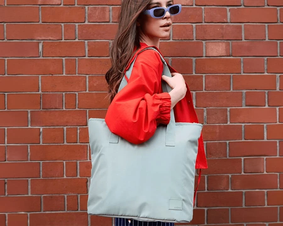 A woman carrying an American Tourister urban groove tote bag