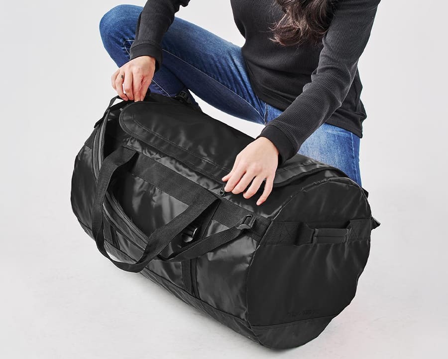 A woman zipping a Stormtech medium gear bag