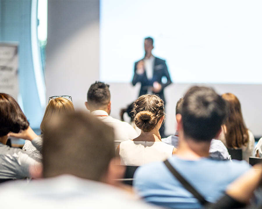 Crowd of people watching a presenter at a conference