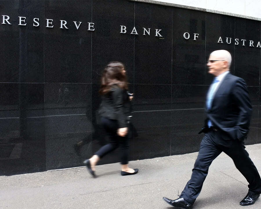 Two people walking past the Reserve Bank of Australia building