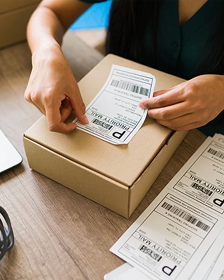 A person placing a delivery label on a package