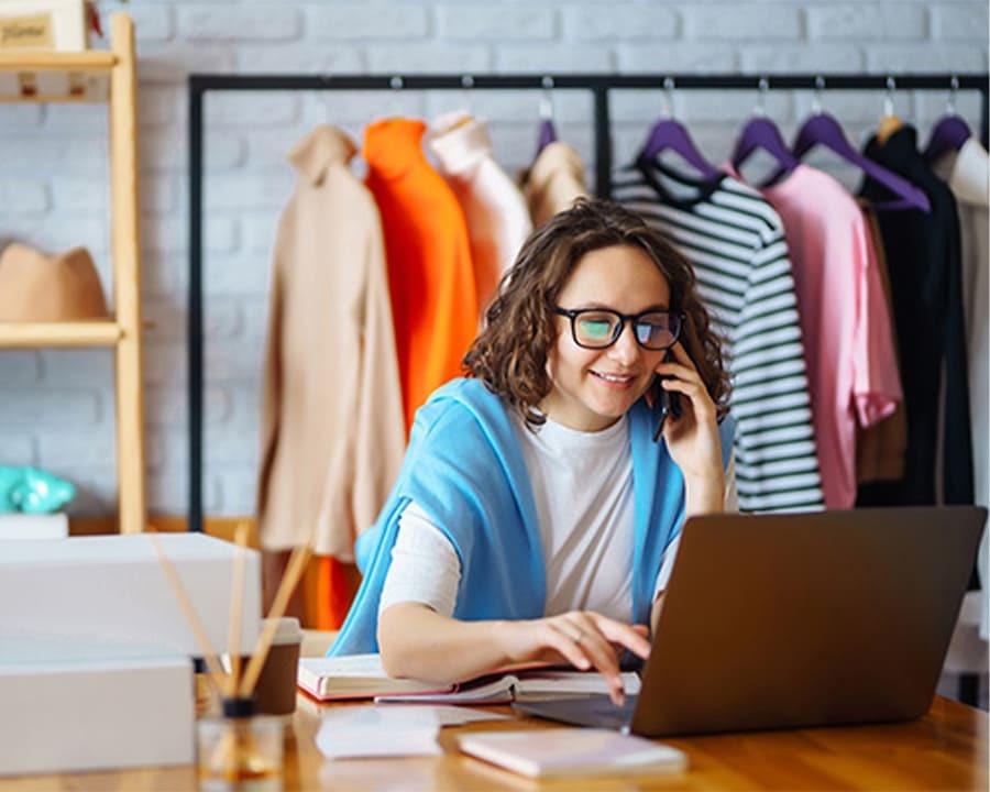 A woman talking on the phone, browsing on her laptop