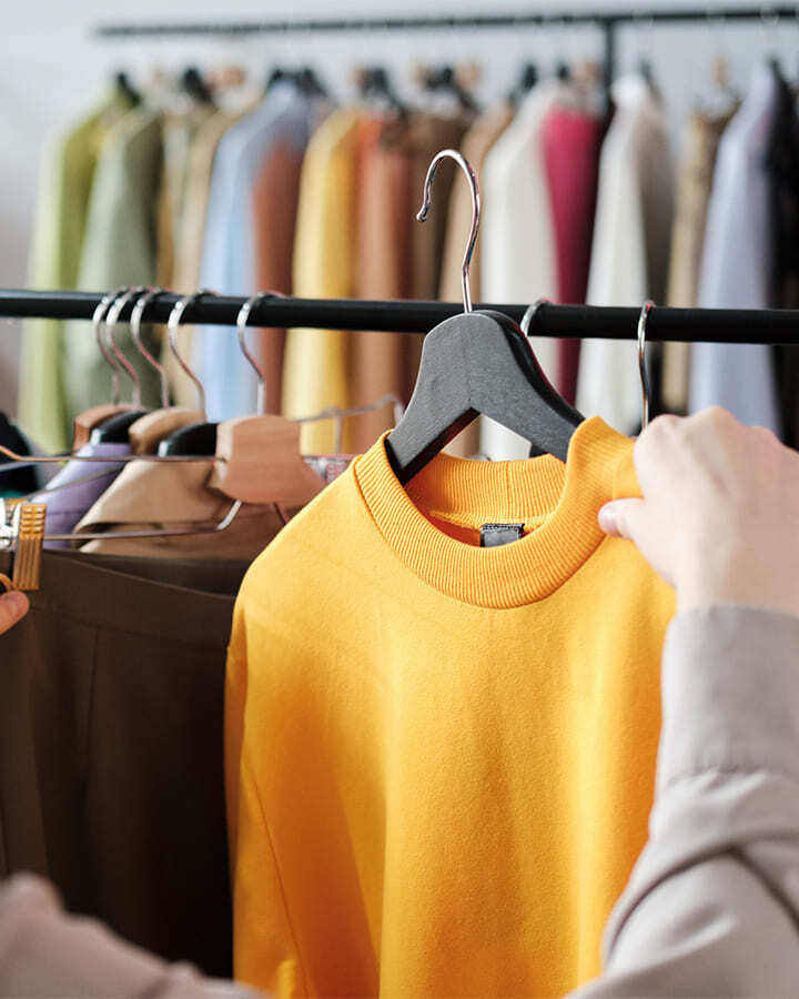 Person browsing bright clothing on a rack