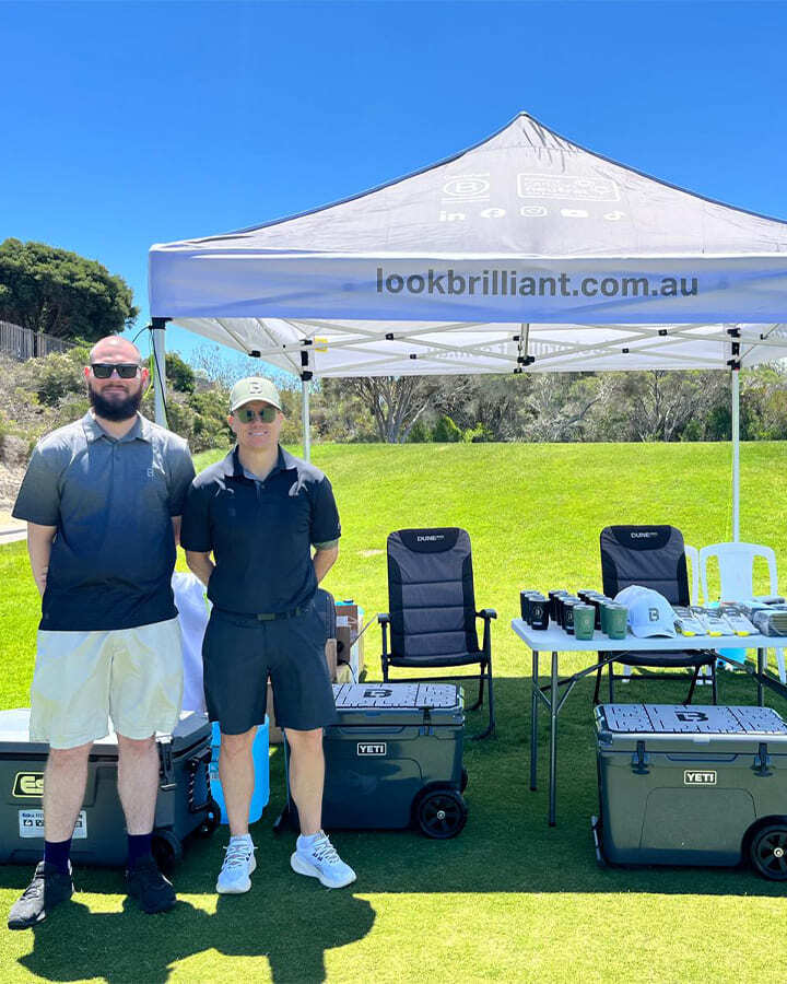 Two Look Brilliant employees standing beside a branded tent