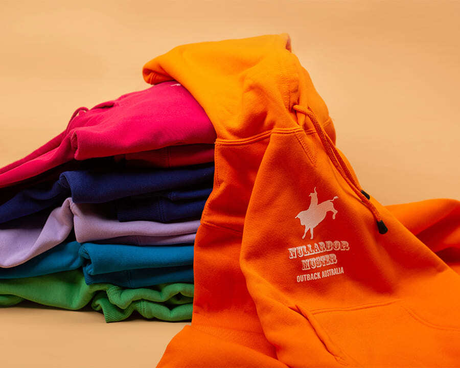 A stack of colourful Nullarbor Muster Club branded hoodies