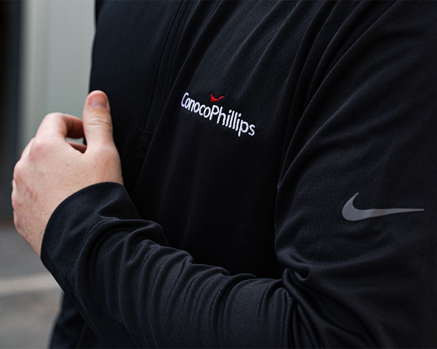 Close-up of a man wearing a black Nike thermal jecket with Conoco Phillips branding