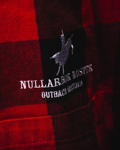 Close-up of a red and black checkered shirt featuring an embroidered logo