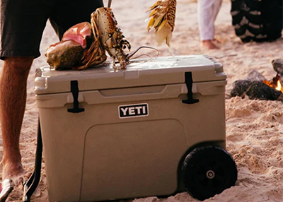 YETI cooler on a sandy beach with seafood on top