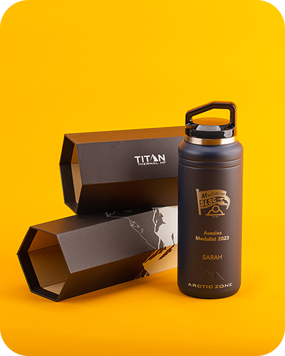 A sleek grey water bottle with engraving, stands beside its hexagonal black box