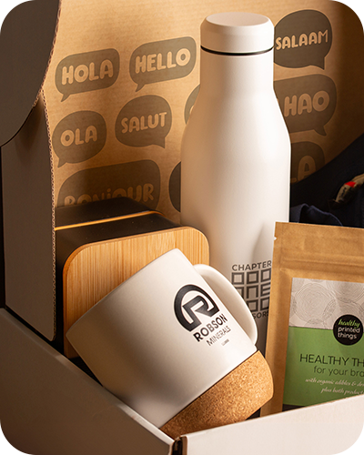 a gift box containing a white reusable bottle, a mug with cork base and a packet of healthy snacks