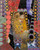 An intricate mixed media artwork by Emma Crisp titled The Kiss, featuring a central collage of Klimt's lovers adorned with gold beads, surrounded by colorful patterns.