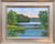 Impressionist oil landscape painting of a blue lake at sunset, surrounded by green trees by Debbie Campbell.
