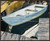 Horizontal impressionist oil painting by Sally Bourdon of a light blue-and-white skiff rowboat tied to a gray wooden dock in a harbor slip.