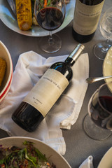 Bottle of seriously old dirt red wine on a table next to various picnic foods