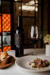 Bottle of Delaire Graff Botmaskop, Stellenbosch 2020 red wine with dark fruit and oak flavors. Bottle of wine next to glass of red wine.