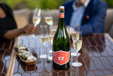 Bottle of Steenberg Sparkling Sauvignon Blanc, Constantia NV sparkling wine with tropical and citrus notes. People sitting at table with bottle of sparkling wines next to glasses of sparkling wine.