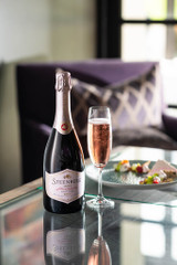 Bottle of Steenberg 1682 Brut Pinot Noir, Constantia NV sparkling wine with fresh berry and citrus. Bottle of sparkling wine next to glass of sparkling wine and plate of food.