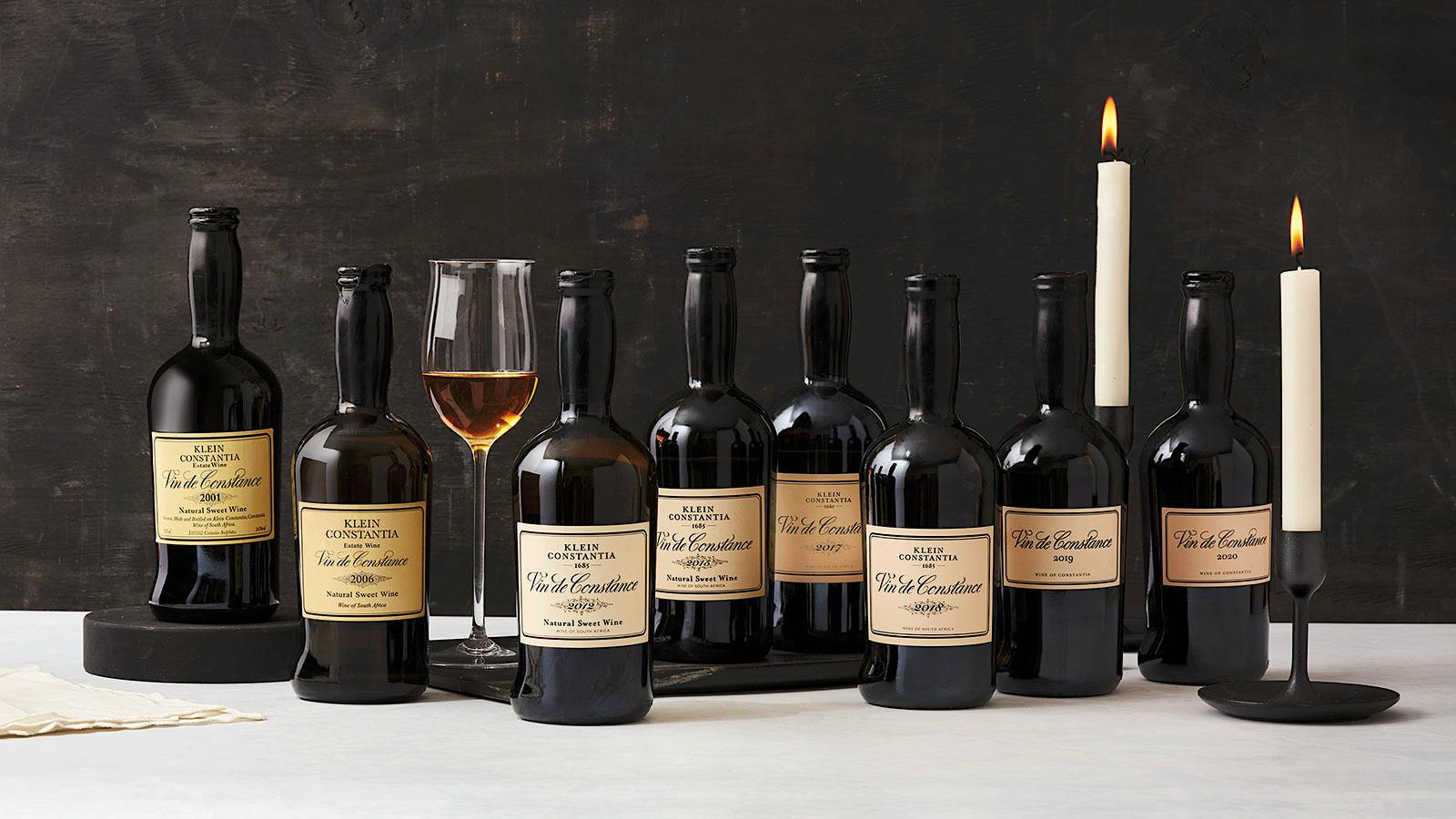 many vintages of vin de constance lined up with candles