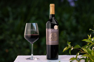 Bottle of Mont Rochelle Cabernet Sauvignon, Franschhoek 2022 red wine with blackberry and oak. Bottle of wine next to glass of red wine.