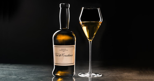 An elegant glass of klein constantia vin de constance next to its bottle