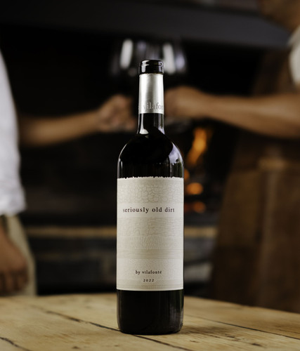 Bottle of seriously old dirt red wine on a table next to a barbecue