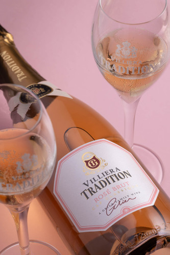 Bottle of Villiera Tradition Brut MCC, Stellenbosch NV sparkling rosé wine with floral notes. Bottle of sparkling wine lying between two glasses of wine.