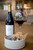 Bottle of Mont Rochelle Little Rock Rouge, Franschhoek 2022 red wine with dark fruit and spice. Bottle of wine next to glass of red wine and plate of food.
