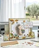Pre-coloured printable clipart of a cute woodland hedgehog holding a bowl filled with acorns and Fall leaves, surrounded by softly coloured falling Autumn leaves and acorns in a delicate watercolour style.