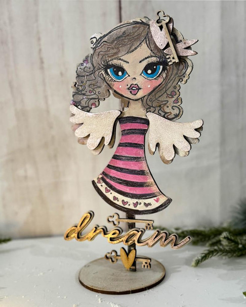 Believe in Angels Forever Angel 3D Mixed Media Craft Kit - Stamps, stencil & MDF bundle, featuring an angel figure with detailed hair, large blue eyes, pink and black striped dress, wings, and a decorative 'dream' sign at the base.