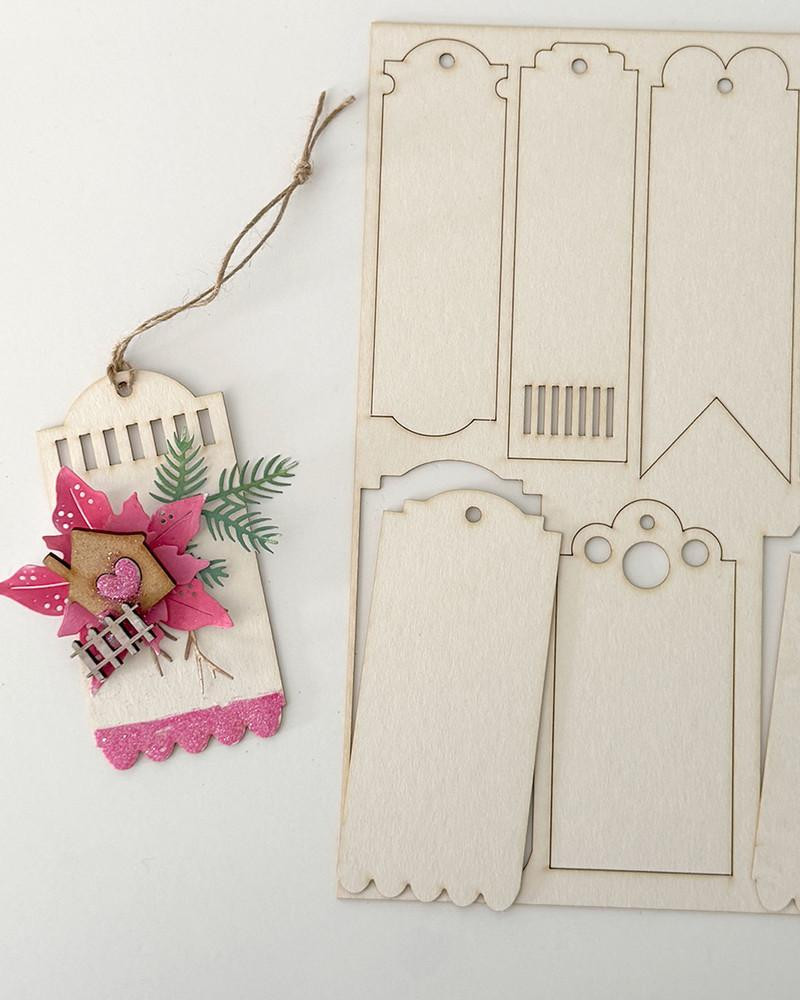 MDF Mixed Media big bundle, including MDF boards, chipboard packs, embroidery hoops, easels, lattice chipboard, and bookmarks, with a decorated pink and green craft tag attached.