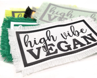 Various colored iron on patches with the words High Vibe Vegan.