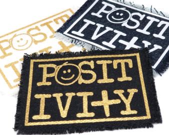 Iron on patches with the word Positivity and a smiley face.