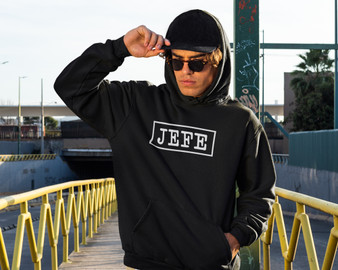 Young man wearing a black hoodie with Jefe printed on front.
