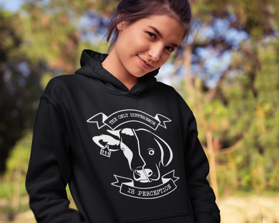Young woman wearing a black hoodie with a design of a half cow face and half dog face and the words the only difference is perception.