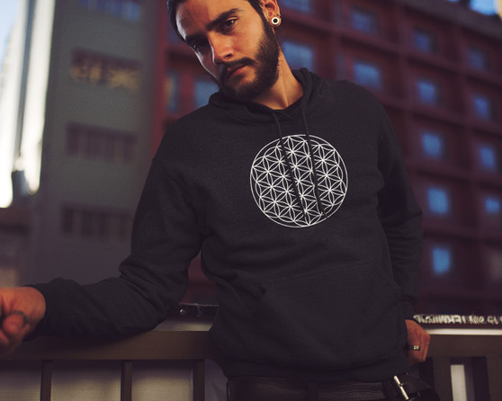 Young urban man wearing a black hoodie with the flower of life sacred geometry symbol on the front.