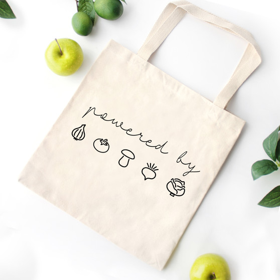 Natural canvas vegan tote bag with the worlds powered by plants printed on it.