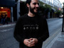 Young man wearing a black hoodie with a white powered by plants design.