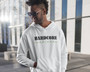 Young man wearing sunglasses and standing in front of an office building wearing a white hoodie with a hardcore herbivore design on it.