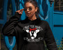 Young woman wearing sunglasses and a black hoodie. Hoodie says Not Your Mom Not Your Milk with a picture of a cow wearing a red bandana.