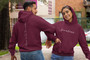 Couple linking arms while wearing maroon hoodies with the word fearless on front and throw me to the wolves on the back.