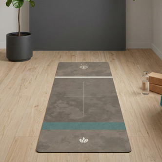 Natural rubber yoga mat laid out on a light wooden floor in a minimalist home yoga space