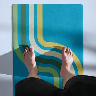 Top-down view of the Retro Pathway yoga mat showing its blue, green and yellow curved stripe design