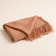 Folded pink blush knit meditation blanket with tassel fringe