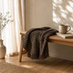 Charcoal knit meditation blanket draped over wooden bench