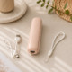 Compact pink portable fan folded for travel with USB charging cable and wrist strap on a neutral background.