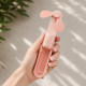 Pink foldable handheld fan held in hand demonstrating lightweight portable summer cooling design.