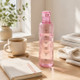 Pink reusable water bottle beside a notebook and coffee cup, perfect for morning routines, home office, study and everyday hydration.