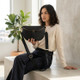 Woman wearing a black leather crossbody bag with adjustable strap, styled casually in a modern living space