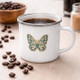 Butterfly enamel mug on wooden table near campfire, lightweight camping coffee cup for outdoor and travel use