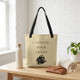 Beige ‘Caffeine Over Chaos’ tote bag on a wooden table in a bright room with a plant and minimalist decor.
